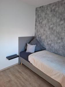a bedroom with a bed with a concrete wall at Ferienwohnung Rose in Altenkunstadt +5 photos