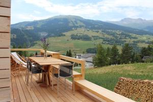 a wooden deck with a table and chairs on a mountain at Ferienwohnung Aviez Savognin in Savognin