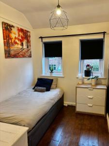 a bedroom with a bed and a desk and two windows at Piotr House in Warrington