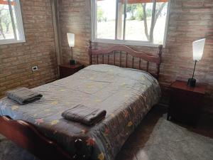 a bedroom with a large bed with two night stands and two windows at Angel Alpino Cabin in Cuesta Blanca +34 photos