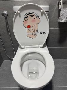 a toilet with a cartoon on the seat in a bathroom at Shinchan homestay in Skudai