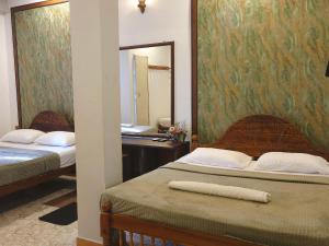 a bedroom with two beds and a desk with a mirror at CTC Receptions in Anuradhapura