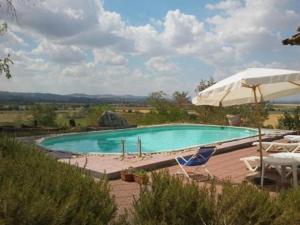 a swimming pool with two chairs and an umbrella at La Pievaccia in Binami