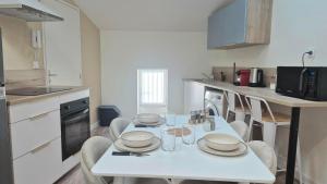 a kitchen with a white table with plates and glasses on it at Sous les Toits Yssoiriens - Centre-Ville in Issoire
