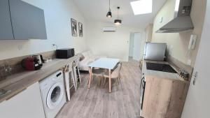 a kitchen with a sink and a table with a washing machine at Sous les Toits Yssoiriens - Centre-Ville in Issoire