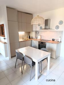 a white kitchen with a white table and chairs at Casa nel parco 3 camere 2 bagni 6 ospiti in Luni