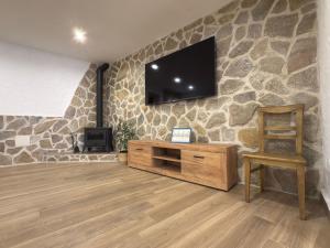 a living room with a tv on a stone wall at Casa Rural Tomillo in Navalcán