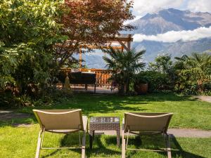 two chairs and a table in the grass with mountains at B&B Chalet Andy in Schenna