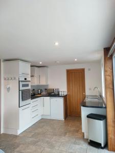 a kitchen with white cabinets and a sink at Townfield Lodge in Bury Saint Edmunds