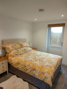 a bedroom with a bed with a yellow comforter and a window at Townfield Lodge in Bury Saint Edmunds
