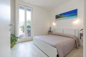 a white bedroom with a bed and a window at Appartamento Tre Api by ElbaSummer in Procchio