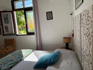 a bedroom with a bed with blue pillows and a window at Le jardin des B-joux - Piscine privée - 3 ch et 3 sdb indépendantes - Grand jardin arboré - Vue mer et Pitons du Carbet - 10 mn de la plage - Propriété fermée - Aucun vis à vis in Le Morne-Vert +42 photos