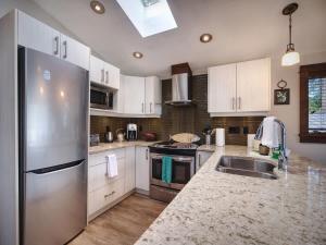 a kitchen with white cabinets and a stainless steel refrigerator at Hera's Cove - Oceanfront Oasis - Pet Friendly in Port Renfrew