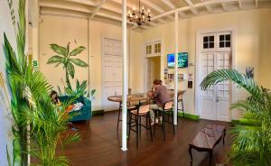 a woman sitting at a table in a room with plants at Ancestral Hostel Barranco in Lima