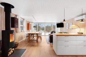 a kitchen with a stove and a dining room with a table at TV1706-Bindslev-Uglevej-7 in Tversted