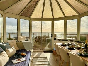 a living room with a large conservatory with a table and chairs at Crows Nest Dawlish in Dawlish