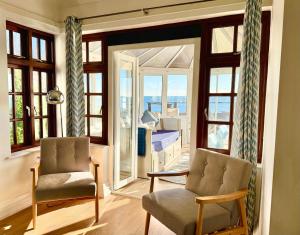 a living room with two chairs and a balcony at Crows Nest Dawlish in Dawlish