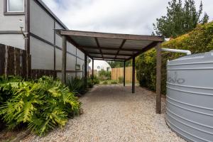 a pergola over a walkway next to a building at Five Elements Resort - Elephant Trailer Tiny House in Harkerville