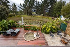 a deck with a hot tub and chairs on it at Five Elements Resort - Elephant Trailer Tiny House in Harkerville