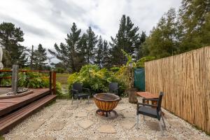 a patio with chairs and a table and a fence at Five Elements Resort - Elephant Trailer Tiny House in Harkerville