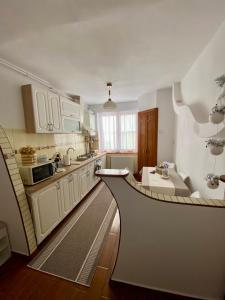 a kitchen with white cabinets and a table in it at Cozy Apartment D&D in Topliţa +9 photos