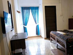 a bedroom with a bed and a window with blue curtains at CTC Receptions in Anuradhapura