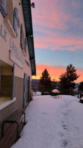 a snow covered building with a bench in the snow at Aupalya Gîte Le Logis Catalan in Font-Romeu