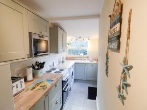 a kitchen with blue cabinets and white appliances at Cobbler's Cottage in Norwich