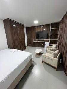 a bedroom with a bed and a couch and a tv at Villa Hotel in Bom Jesus da Lapa