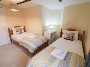 a bedroom with two beds and a night stand at Cobbler's Cottage in Norwich