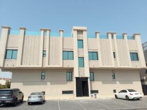 a building with two cars parked in a parking lot at Four Stays Khobar in Al Khobar