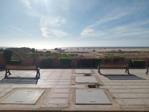 two benches sitting on a patio looking at the beach at Waterfront apartment in Aghroud in Ti nʼ Mansour