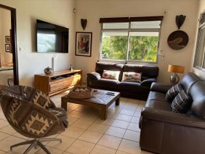 a living room with a couch and a table at Le jardin des B-joux - Piscine privée - 3 ch et 3 sdb indépendantes - Grand jardin arboré - Vue mer et Pitons du Carbet - 10 mn de la plage - Propriété fermée - Aucun vis à vis in Le Morne-Vert