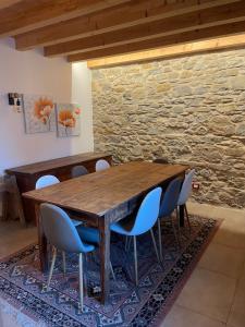 a wooden table with chairs and a stone wall at Casa Riva Us in Dussoi