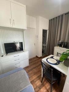 a living room with a table and a tv and a kitchen at KIT 300- com Ar cond - 5 min do aeroporto, rodoviária e embaixadas in Brasília +10 photos