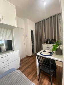 a living room with a table with a chair and a bedroom at KIT 300- com Ar cond - 5 min do aeroporto, rodoviária e embaixadas in Brasília