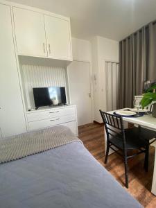 a bedroom with a bed and a desk with a television at KIT 300- com Ar cond - 5 min do aeroporto, rodoviária e embaixadas in Brasília