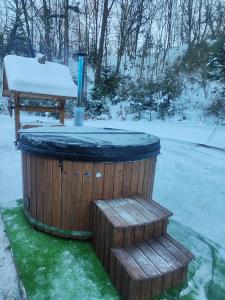 a snow covered hot tub with two wooden steps at Chatka Podzawale in Bircza +1 photo