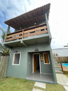 a small green house with a balcony on top at Vila Pimenta Rosa in Caraíva