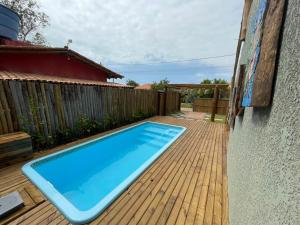 a swimming pool on a wooden deck next to a house at Vila Pimenta Rosa in Caraíva