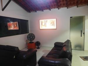 a living room with two leather couches and a fan at Casa - 1 Suíte e 2 Quartos in Saquarema