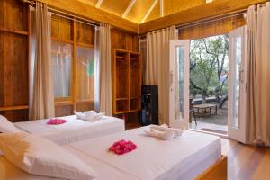 two beds in a room with white sheets and pink flowers at joe Dive resort in Pulau Lembeh