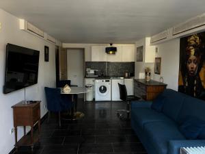 a living room with a blue couch and a kitchen at Résidence P&C Studio élégant proche de Paris in Neuilly-sur-Marne