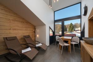 a dining room with chairs and a table and a large window at Aspen Lodge Apartments & Sauna in Černý Dŭl