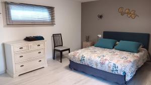 a bedroom with a bed and a chair and a dresser at Le Moulin du Comte in Bourrouillan