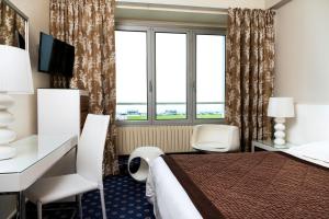 a hotel room with a bed and a desk and window at Hotel Aguado in Dieppe