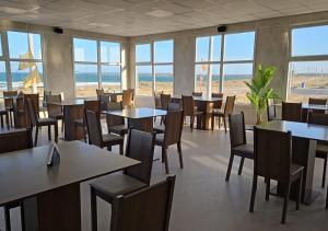 a dining room with tables and chairs and the beach at Ayres Dorados Lodge Hotel in Sierra Grande