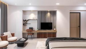 a bedroom with a bed and a desk with a television at Hotel Presidency in Surat