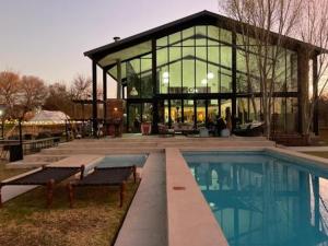 a large glass building with a pool in front of it at Marble Nights Damoi Parys in Vosburg +25 photos