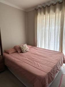 a bedroom with a pink bed with a window at CASA ESPAÇOSA e CONFORTÁVEL EM PARATY in Paraty